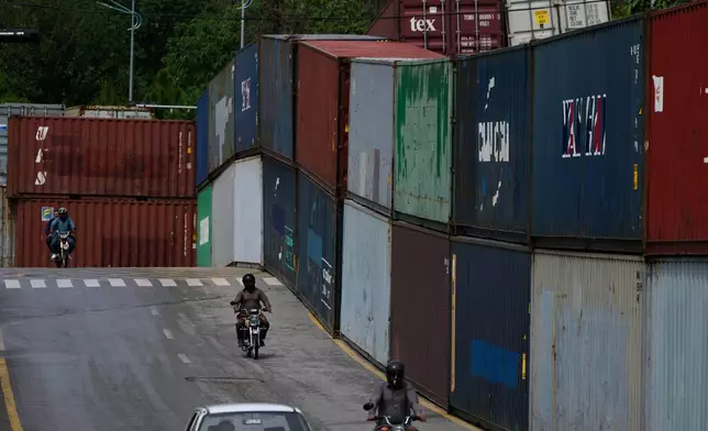 Motorcyclists drive past shipping containers placed by authorities to seal off an area ahead of a plan protest march by the supporters of imprisoned former Prime Minister Imran Khan demanding his release, in Islamabad, Pakistan, Monday, Sept. 28, 2026. (AP Photo/Anjum Naveed)