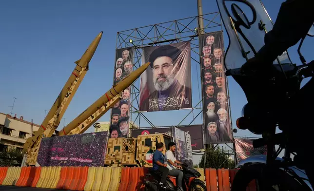 Motorbikes drive past Iranian missiles and banners showing portraits of the Iranian Supreme Leader Ayatollah Mojtaba Khamenei, center, and the late armed forces commanders and nuclear scientists, who were killed in Israeli and U.S. strikes, displayed in a military exhibition commemorating the anniversary of the start of the 1980-88 Iraq-Iran war at Baharestan Square, in Tehran, Monday, Sept. 28, 2026. (AP Photo/Vahid Salemi)