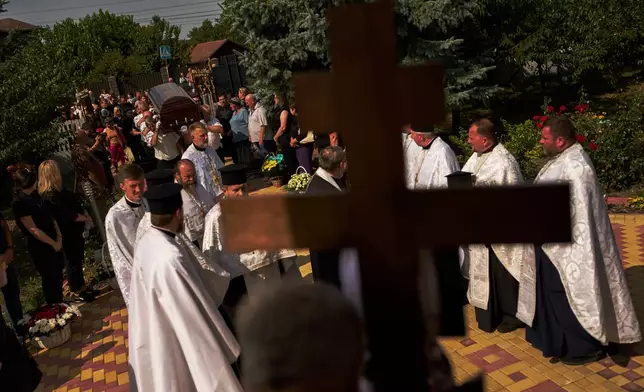 Pallbearers carry the coffin of Taras Didych, head of the Dmytrivska community in Kyiv region who was killed while going to help local residents following a Russian drone attack, during his funeral in Myla on the outskirts of Kyiv, Monday, Aug. 31, 2026. (AP Photo/Francisco Seco)
