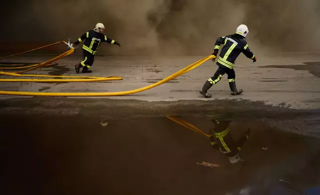 Firefighters try to extinguish a fire at a destroyed warehouse after Russian drone attacks on the outskirts of Kyiv, Ukraine, Friday, Aug. 28, 2026. (AP Photo/Francisco Seco)