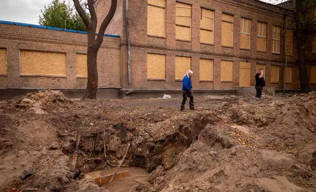 A man walks past a crater left after a Russian attack at an elementary school in Kyiv, Tuesday, Sept. 1, 2026. (AP Photo/Dan Bashakov)