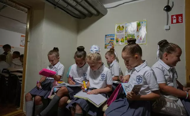 Schoolgirls work on a lesson in a bomb shelter during a Russian air attack on the first day at school at a cadet lyceum in Kyiv, Ukraine, Tuesday, Sept. 1, 2026. (AP Photo/Efrem Lukatsky)