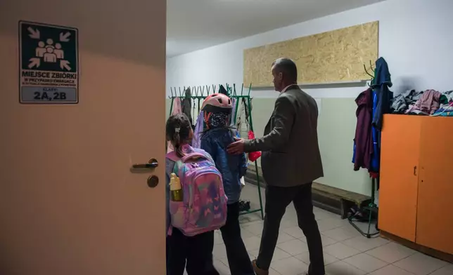 Jarosław Wojcik, the school principal guides children into a school cloakroom, which has been converted into a makeshift bomb shelter, in Dorohusk, Poland, on Sept. 24, 2026. (AP Photo/Attila Husejnow)