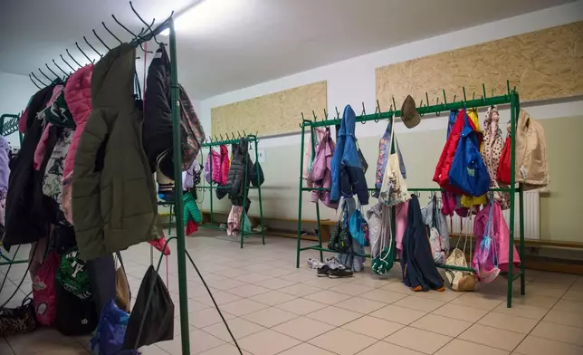 Children's jackets and bags hang on racks inside a school cloakroom that has been converted into a makeshift bomb shelter to ensure safety for students in Dorohusk, Poland, on Sept. 24, 2026. (AP Photo/Attila Husejnow)