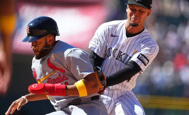 Colorado Rockies shortstop Ezequiel Tovar, right, tags out St. Louis Cardinals pinch runner Victor Scott II, left, in a rundown between first base and second base in the seventh inning of a baseball game Sunday, Sept. 6, 2026, in Denver. (AP Photo/David Zalubowski)