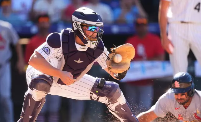 Colorado Rockies catcher Hunter Goodman, left, fields the throw as St. Louis Cardinals' José Fermín, bottom right, scores on a double hit by Iván Herrera in the eighth inning of a baseball game Sunday, Sept. 6, 2026, in Denver. (AP Photo/David Zalubowski)