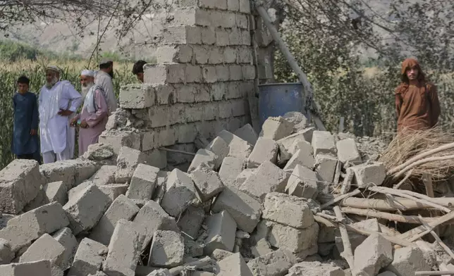 Residents stand near a collapsed wall of a house damaged in a strike in Patan village, Kunar province, eastern Afghanistan, Monday, Sept. 21, 2026. (AP Photo/Shafiullah Kakar)