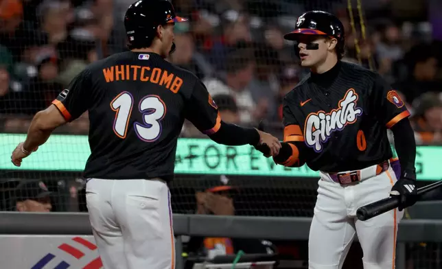 San Francisco Giants' Shay Whitcomb (13) is congratulated by Drew Gilbert (0) after scoring on a sacrifice by Drew Cavanaugh during the second inning of a baseball game against the Minnesota Twins in San Francisco, Tuesday, Sept. 22, 2026. (AP Photo/Jed Jacobsohn)