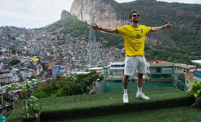 A tourist wearing a jersey in Brazilian colors poses for photos on a terrace at the Rocinha favela in Rio de Janeiro, on Sept. 2, 2026. (AP Photo/Silvia Izquierdo)