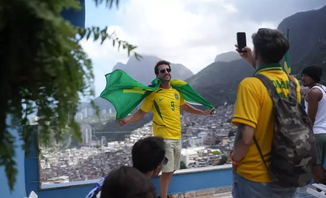 A tourist wearing a jersey in Brazilian colors poses for a photo at the Rocinha favela in Rio de Janeiro, on Sept. 2, 2026. (AP Photo/Silvia Izquierdo)