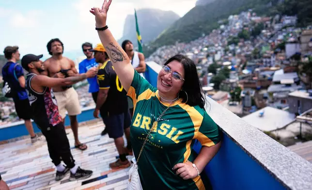 Italian tourist Edda Di Dato, wearing a Brazil's jersey, strikes a pose at a terrace in the Rocinha favela in Rio de Janeiro, on Sept. 2, 2026. (AP Photo/Silvia Izquierdo)