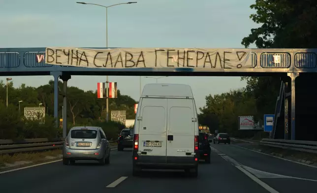 Cars pass under a pedestrian bridge with a banner on it reading: "Eternal glory, General! (former Bosnian Serb wartime general Ratko Mladic)" in Belgrade, Serbia, Thursday, Sept. 3, 2026. (AP Photo/Darko Vojinovic)