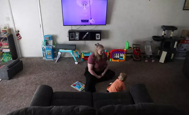 Meygan Maloney does a Mickey Mouse puzzle with her son Callum Wilson, 3, Friday, Aug. 28, 2026, at their home in Hartford City, Ind. (AP Photo/Cara Penquite)