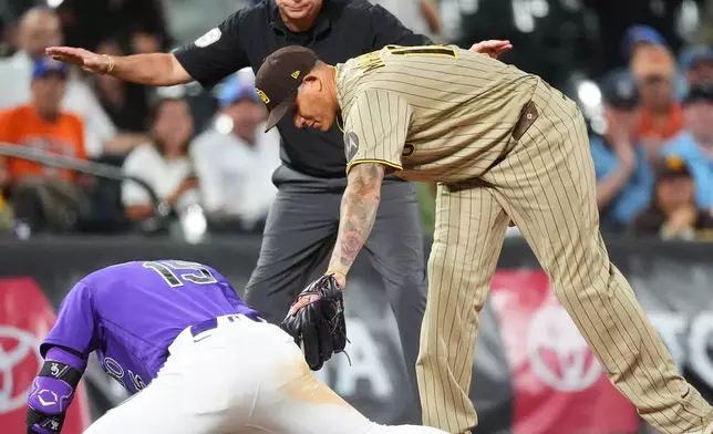 Colorado Rockies' Hunter Goodman, front left, slides into third base for a triple as San Diego Padres third baseman Manny Machado, front right, applies a late tag while third base umpire Andy Fletcher makes the call in the sixth inning of a baseball game Monday, Sept. 14, 2026, in Denver. (AP Photo/David Zalubowski)