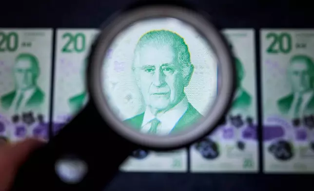The portrait of King Charles III on the new Canadian $20 note is seen under a magnifying glass at its unveiling event in Ottawa, on Thursday, Sept. 3, 2026. (Justin Tang/The Canadian Press via AP)