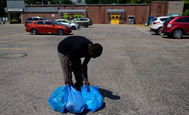 Harounat Sarre, a Mauritanian immigrant, rearranges his groceries in the parking lot of Valley Interfaith Community Resource Center as he walks to his shared apartment in Lockland, Ohio, Friday, July 31, 2026. (AP Photo/Carolyn Kaster)