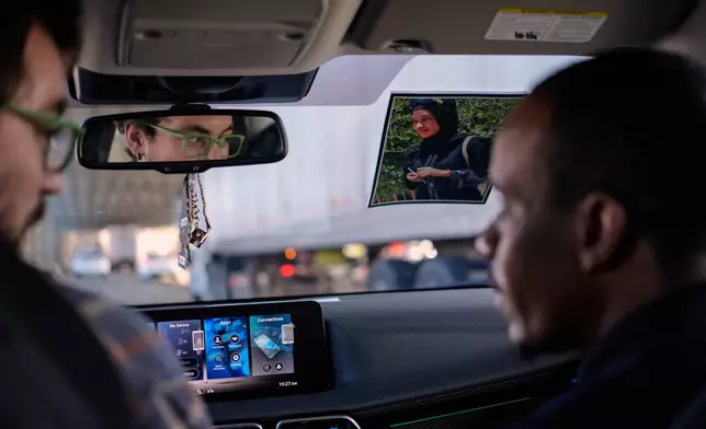A photo of Samba Diallo's wife hangs from the inside of his car as he's driven home by Vincent Wilson, left, following an Immigration and Customs Enforcement appointment in Cincinnati, Monday, Sept. 14, 2026. Diallo posts the picture of his wife, who still lives in their native Mauritania, on the inside of his windshield to see her whenever he drives. (AP Photo Carolyn Kaster)