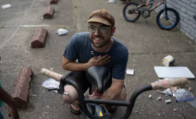 Vincent Wilson, who takes in donated, broken bikes and offers them up to the community for anyone who helps fix them up, looks up as he fixes a bike in front of Bikes and Stuff in Lockland, Ohio, Friday, July 17, 2026. (AP Photo/Carolyn Kaster)