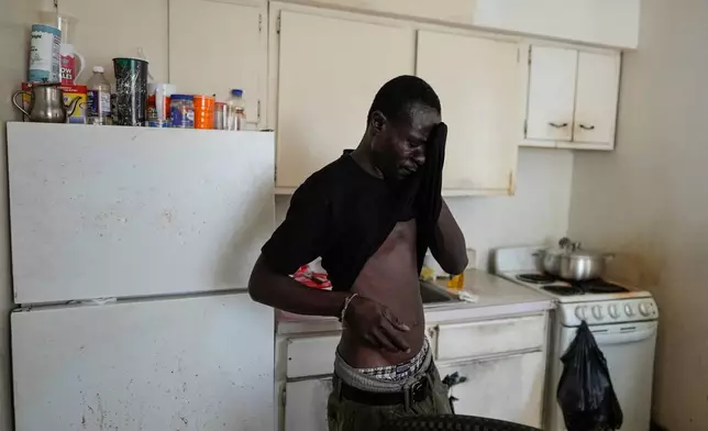 Harounat Sarre, a Mauritanian immigrant, wipes away sweat after unpacking groceries from a food pantry into the refrigerator of his shared apartment in Lockland, Ohio, Friday, July 31, 2026. (AP Photo/Carolyn Kaster)
