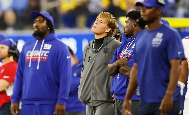 New York Giants quarterback Jaxson Dart, center, watches from the sideline during the second half of an NFL football game against the Los Angeles Rams in Inglewood, Calif., Monday, Sept. 21, 2026. (AP Photo/Caroline Brehman)