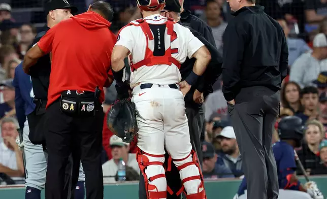 A game delay was called after the home plate umpire, far left, was hit by a pitch during the sixth inning of a baseball game between the Boston Red Sox and Seattle Mariners, Tuesday, Sept. 1, 2026, in Boston. (AP Photo/Mark Stockwell)