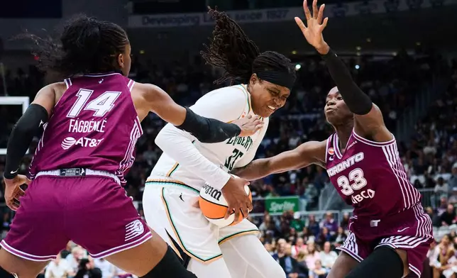 New York Liberty's Jonquel Jones (35) drives to the net through Toronto Tempo's Temi Fagbenle (14), left, and Ornella Bankole (33) during the first half of a WNBA basketball game in Toronto, Sunday, Sept. 20, 2026. (Sammy Kogan/The Canadian Press via AP)