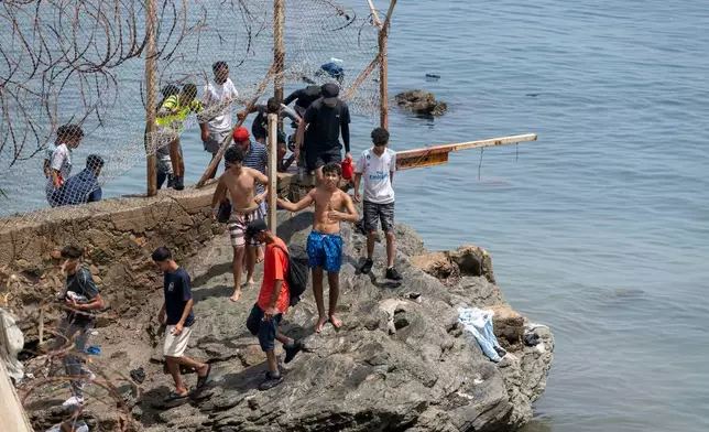 FILE - People breach barbed wires as they attempt to cross from the Moroccan northern town of Fnideq to the Spanish enclave of Ceuta, July 31, 2026. (AP Photo, File)