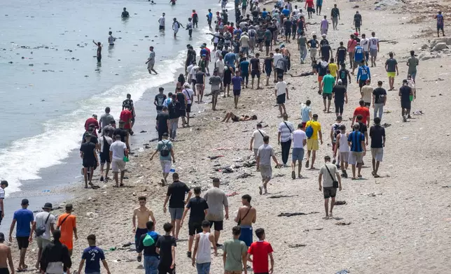 FILE - People walk on a beach after attempting to cross from the Moroccan northern town of Fnideq to the Spanish enclave of Ceuta, July 31, 2026. (AP Photo, File)