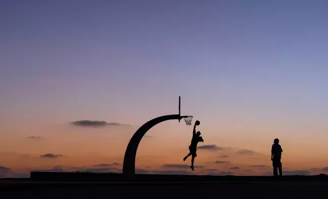People play basketball in a park at dusk in the San Pedro neighborhood of Los Angeles, Monday, Aug. 31, 2026. (AP Photo/Jae C. Hong)