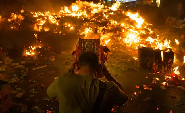 An ethnic Chinese devotee throws paper offerings into a fire during the Hungry Ghost Festival in Bukit Metajam, Malaysia, Saturday, Aug. 29, 2026. (AP Photo/Vincent Thian)