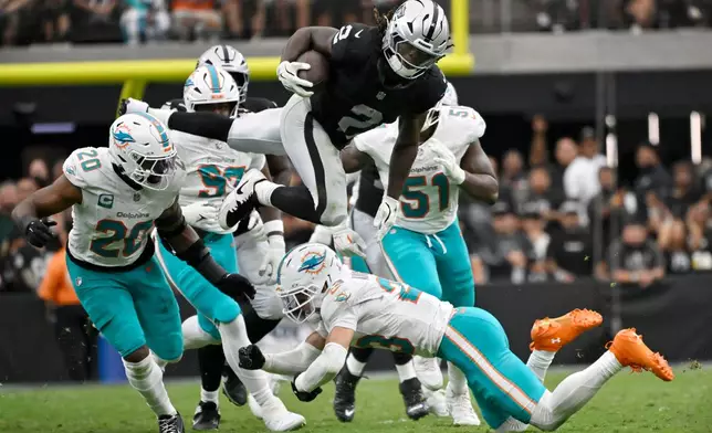Las Vegas Raiders running back Ashton Jeanty (2) leaps over Miami Dolphins linebacker Jordyn Brooks (20) and safety Zayne Anderson (23) during the second half of an NFL football game, Sunday, Sept. 13, 2026, in Las Vegas. (AP Photo/David Becker)