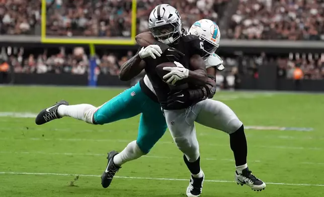 Las Vegas Raiders running back Ashton Jeanty tries to break a tackle by Miami Dolphins linebacker Jordyn Brooks, rear, during a touchdown catch in the second half of an NFL football game, Sunday, Sept. 13, 2026, in Las Vegas. (AP Photo/Ross D. Franklin)