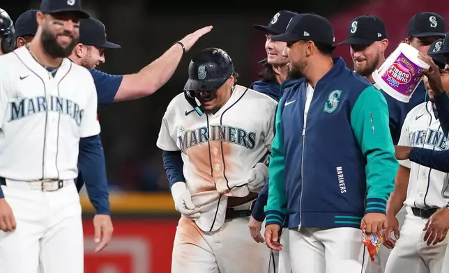 Seattle Mariners' Josh Naylor, center, celebrates with teammates after hitting a walk-off RBI single against the Houston Astros in the 10th inning of a baseball game, Wednesday, Sept. 23, 2026, in Seattle. (AP Photo/Lindsey Wasson)