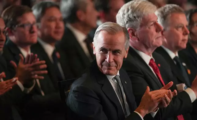 Canada Prime Minister Mark Carney applauds while sitting with Minister of Energy and Natural Resources Tim Hodgson before speaking after LNG Canada said it will go ahead with the Phase 2 expansion project at its LNG terminal in Kitimat, British Columbia, Canada, during an announcement in Vancouver, on Tuesday, Sept. 29, 2026. (Darryl Dyck/The Canadian Press via AP)