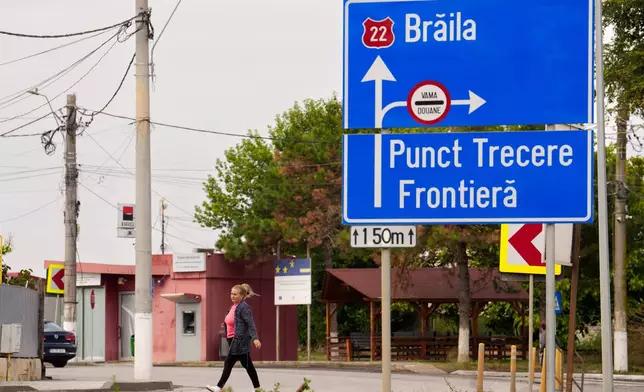 A woman walks by a traffic sign showing the way to a border crossing point in Isaccea, a town on the Romanian-Ukrainian border, Romania, Monday, Sept. 14, 2026. (AP Photo/Vadim Ghirda)