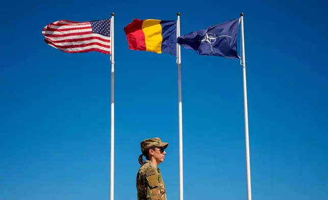 U.S. Staff Sergeant Alyssa Blom walks by flags at the Mihail Kogalniceanu Air Base, in Mihail Kogalniceanu, Romania, Thursday, Sept. 10, 2026. (AP Photo/Andreea Alexandru)