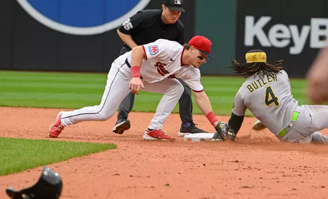 Cleveland Guardians' Travis Bazzana, front left, tags out Athletics' Lawrence Butler (4) on a steal-attempt as umpire Junior Valentine, back left, watches during the seventh inning of a baseball game, Sunday, Sept. 20, 2026, in Cleveland. (AP Photo/Phil Long)