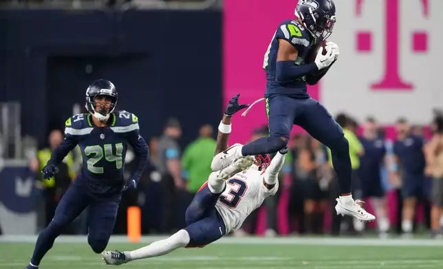 Seattle Seahawks safety Julian Love (20) intercepts a pass intended for New England Patriots wide receiver DeMario Douglas (3) as New England Patriots safety Dell Pettus (24) looks on during the second half of an NFL football game, Wednesday, Sept. 9, 2026, in Seattle. (AP Photo/Lindsey Wasson)