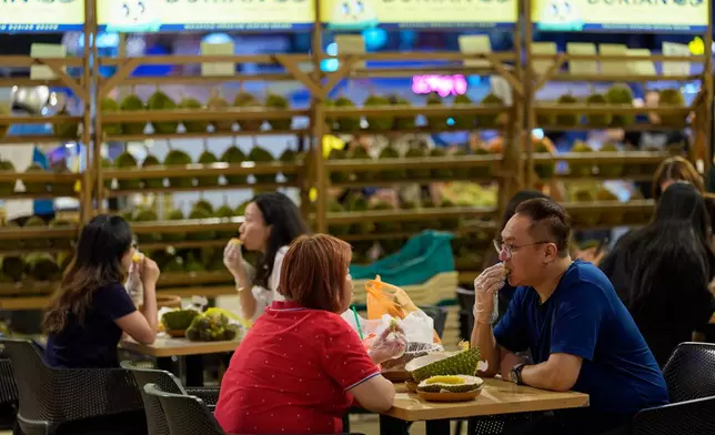 Customers eat durian at a durian stall in Petaling Jaya, on the outskirts of Kuala Lumpur, Malaysia, Monday, June 22, 2026. (AP Photo/Vincent Thian)