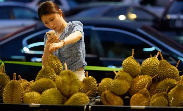 A Chinese tourist take picture of a durian at a durian stall in Petaling Jaya, on the outskirts of Kuala Lumpur, Malaysia, Monday, June 22, 2026. (AP Photo/Vincent Thian)