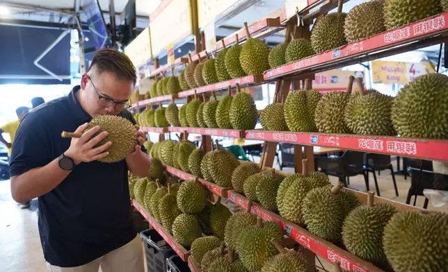 A man smells a durian at a durian stall in Petaling Jaya, on the outskirts of Kuala Lumpur, Malaysia, Monday, June 22, 2026. (AP Photo/Vincent Thian)