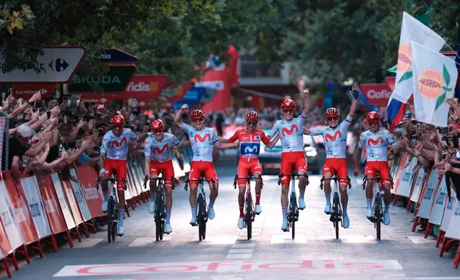 Spain's Enric Mas, center, flanked by his teammates, crosses the finish line during the 21st stage of the Spanish Vuelta cycling race, from Carrefour Granada to Granada, Spain, Sunday, Sept. 13, 2026. (AP Photo/Gregorio Marrero)