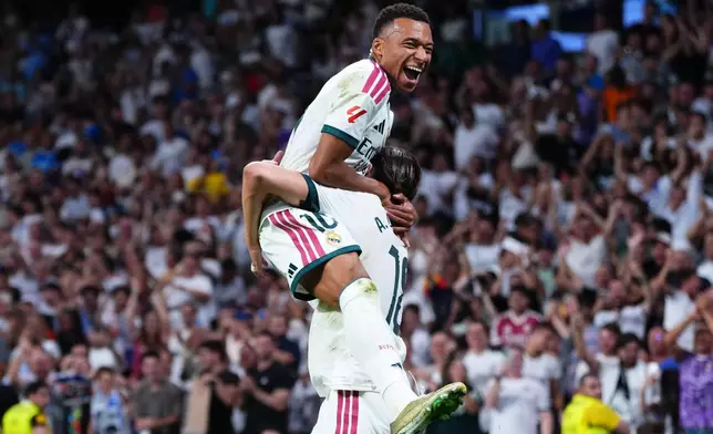 Real Madrid's Alvaro Carreras, bottom, is congratulated by Kylian Mbappe after scoring his side's 2nd goal during the Spanish La Liga soccer match between Real Madrid and Rayo Vallecano in Madrid, Spain, Saturday, Sept. 12, 2026. (AP Photo/Manu Fernandez)