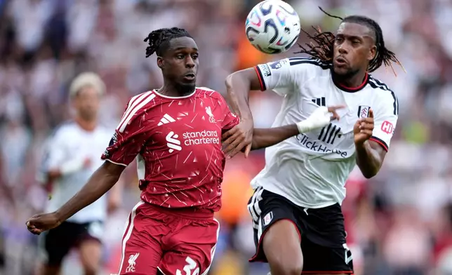 Liverpool's Jeremie Frimpong, left, and Fulham's Alex Iwobi battle for the ball during the English Premier League soccer match between Liverpool and Fulham in Liverpool, England, Saturday Sept. 12, 2026. (Peter Byrne/PA via AP)