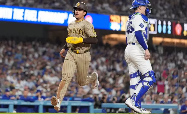 San Diego Padres' Ethan Salas, left, scores on a sacrifice fly by Dustin Harris as Los Angeles Dodgers catcher Hunter Feduccia stands by during the sixth inning of a baseball game Thursday, Sept. 24, 2026, in Los Angeles. (AP Photo/Mark J. Terrill)
