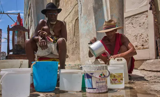 Oscar Joaquín López, left, and his housemate Wilfredo Cisneros Duarte collect water from a street pipe in Havana, Cuba, Monday, Sept. 7, 2026. (AP Photo/Ramon Espinosa)