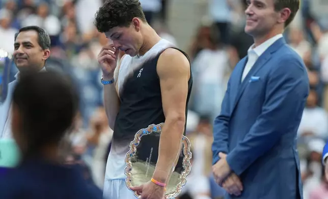 Ben Shelton, of the United States, reacts with a trophy after he lost the men's singles final of the U.S. Open tennis championships against Alexander Zverev, of Germany, Sunday, Sept. 13, 2026, in New York. (AP Photo/Kirsty Wigglesworth)