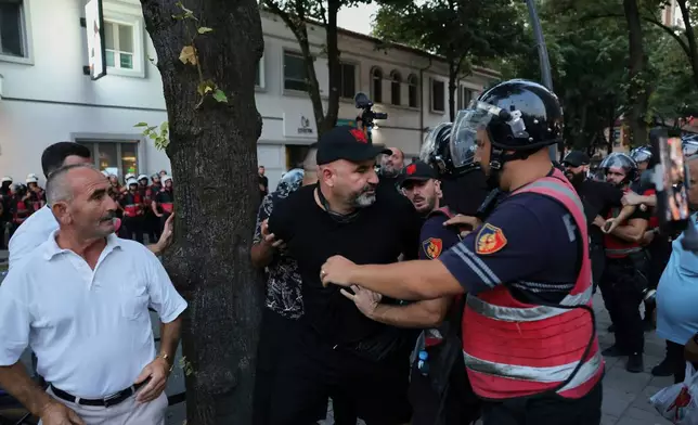 Police officers try to detain a protester during ongoing demonstrations against plans for a luxury resort in a protected coastal area linked to Jared Kushner, U.S. President Donald Trump's son-in-law, in Tirana, Albania, Tuesday, Sept. 8, 2026. (AP Photo/Hameraldi Agolli)