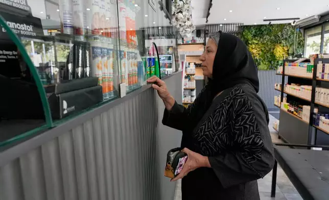A woman receives her medicine at a pharmacy in Tehran, Iran, Friday, Aug. 21, 2026. (AP Photo/Vahid Salemi)
