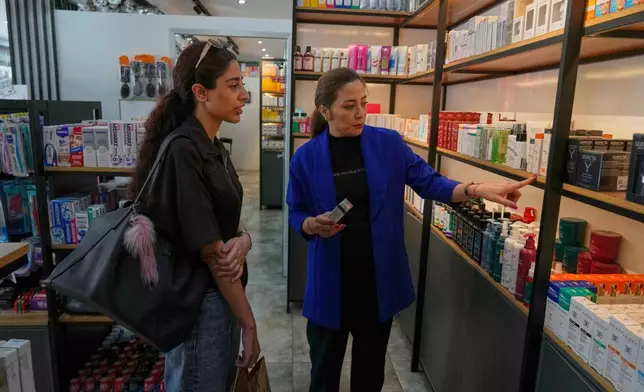 Pharmacy technician Mina Mohammadian talks about cosmetics to a customer at a pharmacy in Tehran, Iran, Friday, Aug. 21, 2026. (AP Photo/Vahid Salemi)
